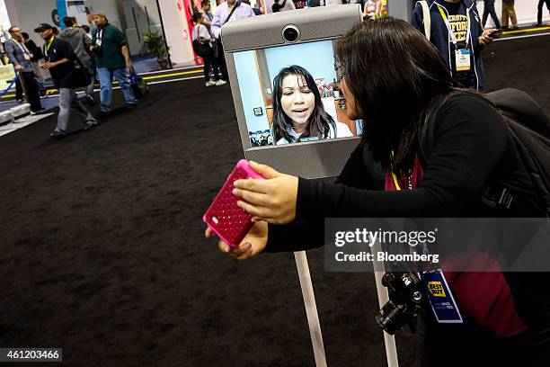 An attendee takes a "selfie" photograph while having a video chat via Beam, a remote presence system manufactured by Suitable Technologies Inc.,...