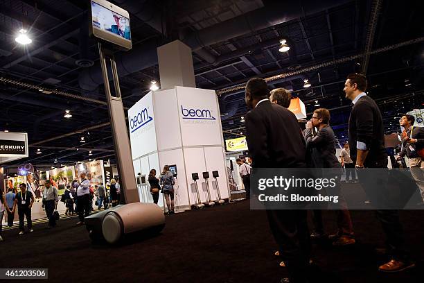 Attendees look up at a large scale Beam+, a remote presence system manufactured by Suitable Technologies Inc., during the 2015 Consumer Electronics...