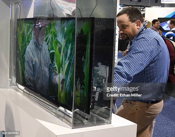An attendee looks at a working television immersed in water at the HZO booth at the 2015 International CES at the Las Vegas Convention Center on...