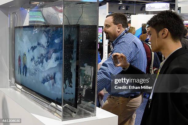 Attendees look at a working television immersed in water at the HZO booth at the 2015 International CES at the Las Vegas Convention Center on January...