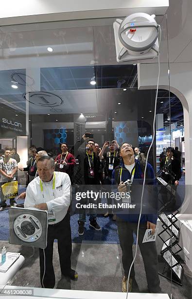 Attendees watch two WINBOT W930 window cleaning robots from Ecovacs Robotics work on either side of a window at the 2015 International CES at the Las...