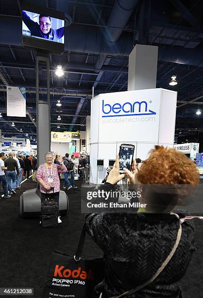 Judy Taylour poses for a photo under a 20-foot-high "MEGABEAM" Smart Presence system with Taylor Lambert appearing on the screen at the 2015...