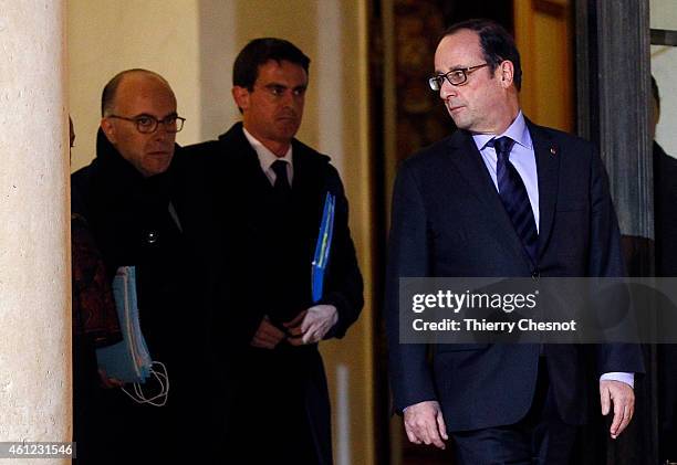 French President Francois Hollande talks with French Prime Minister Manuel Valls next to French Interior Minister Bernard Cazeneuve after holding a...