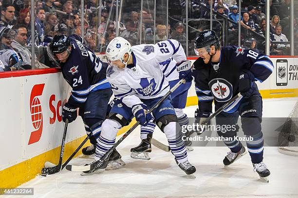 Bryan Little of the Winnipeg Jets watches as teammate Grant Clitsome protects the puck along the boards from Mike Santorelli of the Toronto Maple...