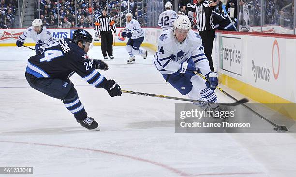 Morgan Rielly of the Toronto Maple Leafs plays the puck down the ice as Grant Clitsome of the Winnipeg Jets defends during third period action on...