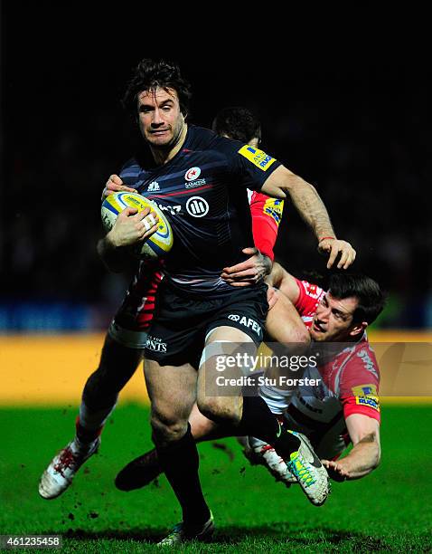 Saracens centre Marcelo Bosch breaks through the tackles of Jonny May and Mark Atkinson of Gloucester during the Aviva Premiership match between...