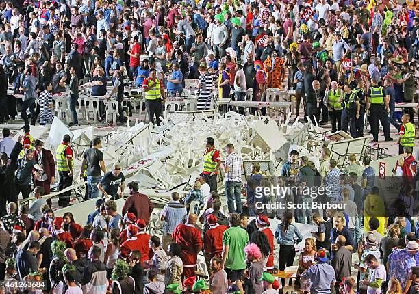 Security and police officers stand guard around a pile of plastic chairs and tables after spectators threw them during the final between Simon The...