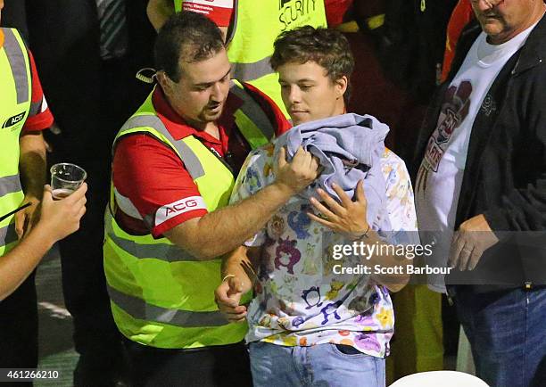 An injured spectator is assisted by a security guard after chairs and tables were thrown by spectators during the final between Simon The Wizard...