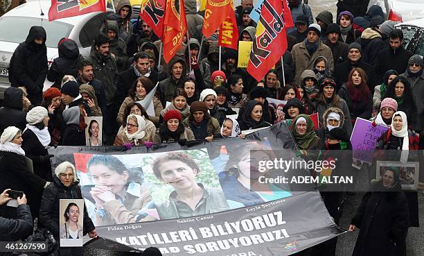 Kurdish people stand behind a banner reading "We know the killers, we want them to be accountable" and bearing photos of the three killed kurdish...