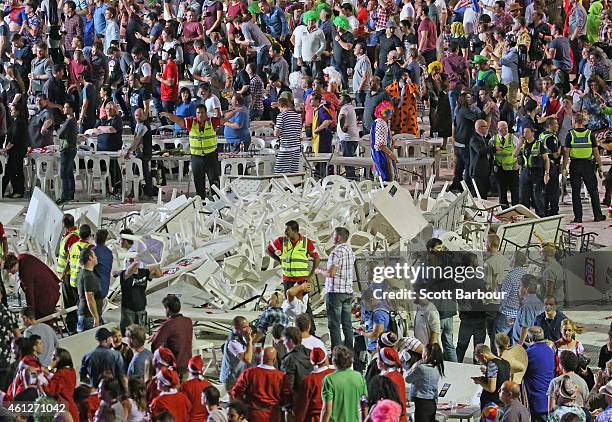 Security guards stand around a pile of plastic chairs and tables after spectators threw them during the final between Simon The Wizard Whitlock and...