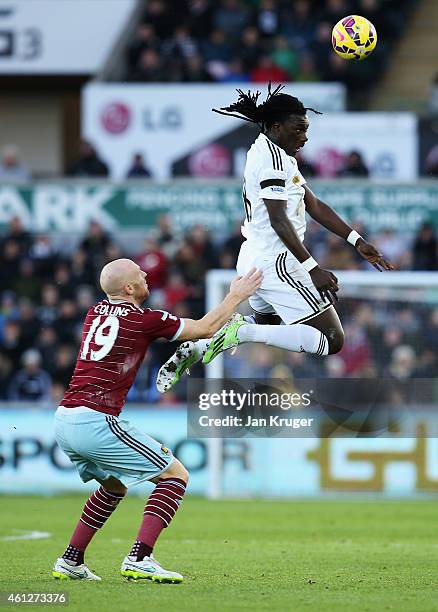 Bafetimbi Gomis of Swansea City wins a header with James Collins of West Ham United during the Barclays Premier League match between Swansea City and...