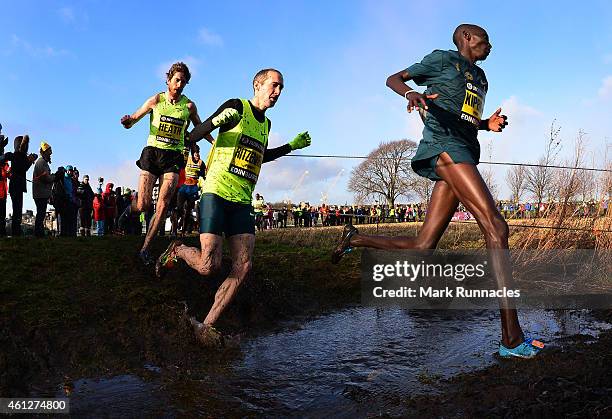 Garrett Heath of USA, Dathan Ritzenhein of USA and Abel Kiprop of Kenya crosses a burn as he competes in the invitational menÕs 4k race during the...