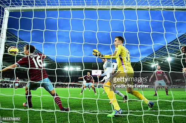 Wwest Ham player Mark Noble and goalkeeper Adrian are unable to stop a header from Bafetimbi Gomis of Swansea going into the net for the Swansea...