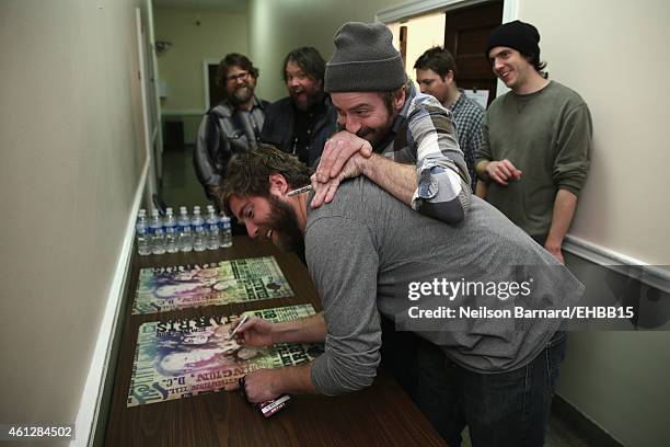 Dave Carroll and Dave Simonett of Trampled By Turtles sign a poster at The Life & Songs of Emmylou Harris: An All Star Concert Celebration at DAR...