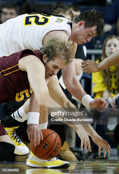 Ricky Doyle of the Michigan Wolverines scrambles for a loose ball against Elliott Eliason of the Minnesota Golden Gophers during the second half at...