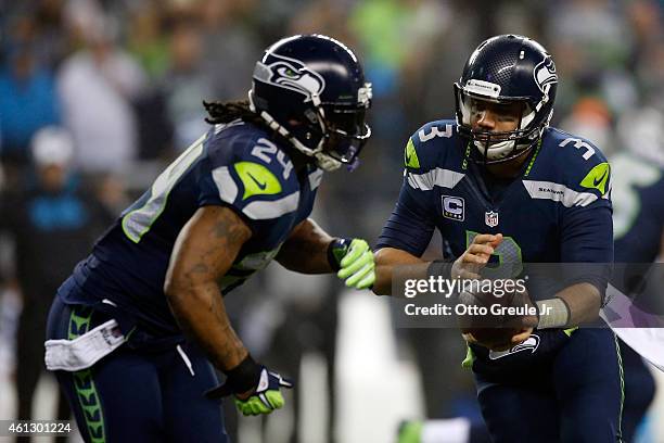 Russell Wilson of the Seattle Seahawks hands off the ball to Marshawn Lynch in the first quarter against the Carolina Panthers during the 2015 NFC...