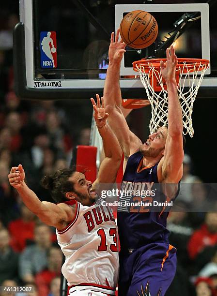 Joakim Noah of the Chicago Bulls gets off a shot under pressure from Miles Plumlee of the Phoenix Suns at the United Center on January 7, 2014 in...