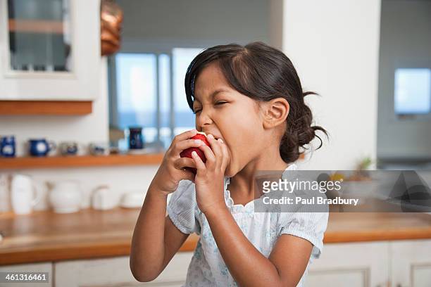 girl in kitchen eating red apple - apple bite out stock pictures, royalty-free photos & images
