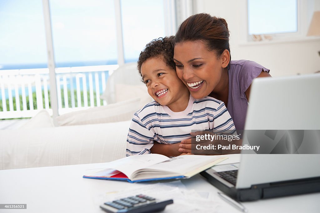 Mother and son at laptop laughing