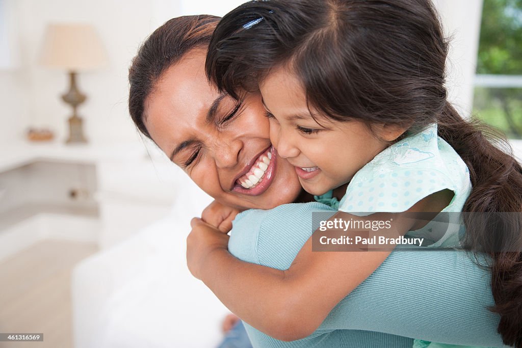 Mother hugging daughter in living room