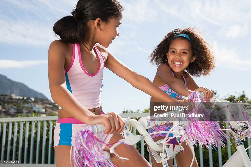 Two girls riding bicycles outdoors smiling