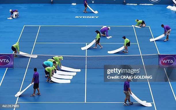 Ground staff attempt to dry the courts after constant rain on day one of the Sydney International tennis tournament in Sydney on January 11, 2015....