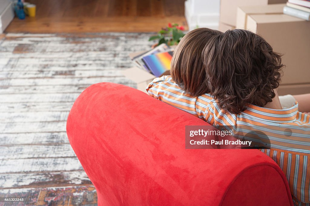 Rear view of couple on red chair in house with cardboard boxes