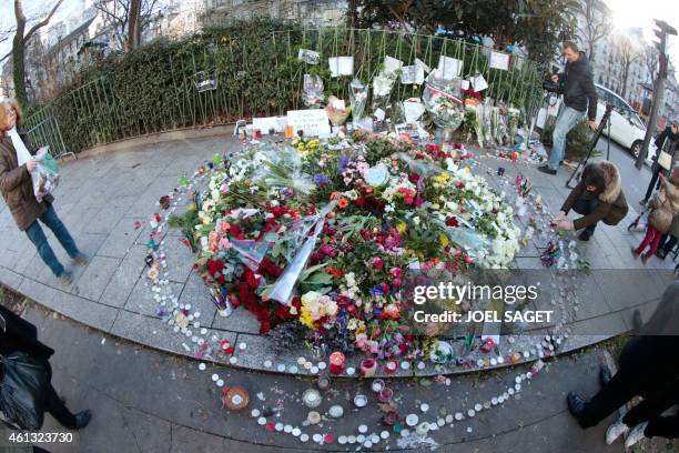 People lay flowers and candles close to the neighberhood where French nationals Cherif and Said Kouachi attacked, on Januray 7, the offices of the...