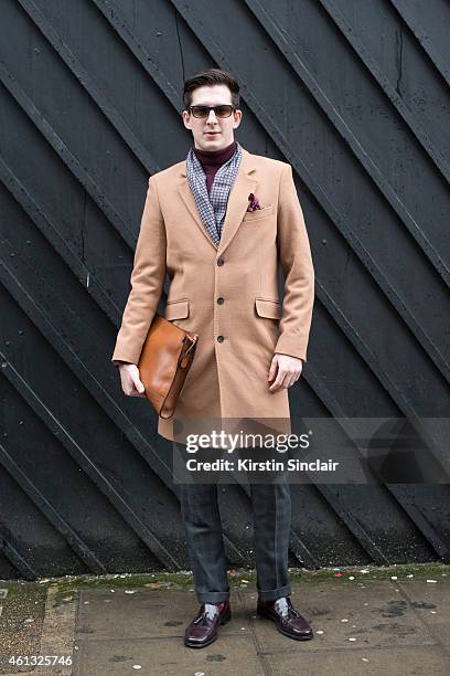 Fashion photographer Ben Lawley wearing an Asos coat, Moss Bros trousers, Herring shoes and a Massimo Dutti clutch bag on day 2 of London...