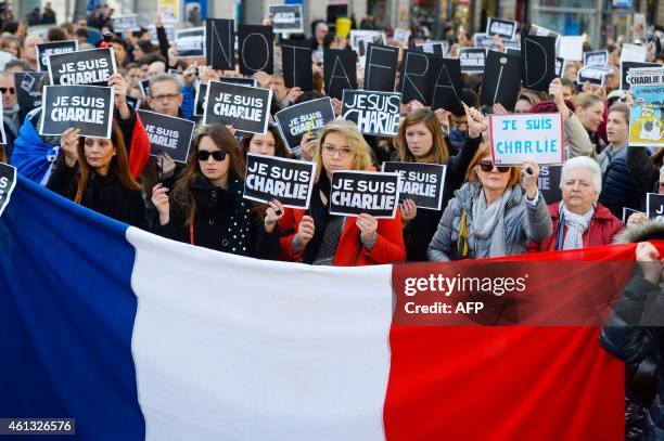 People hold placards reading in French "I am Charlie" behind a french flag during a public show of solidarity at Plaza del Sol in Madrid on January...