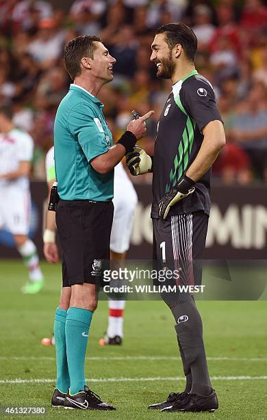 Australian referee Ben Williams shares a light moment with Iran's goalkeeper Ali Reza Haghighi during their football match against Bahrain at the AFC...