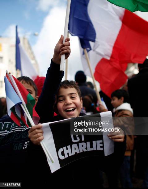 Palestinian kids holds a placard reading in Arabic "I am Charlie" on January 11, 2015 in the center of the West Bank city of Ramallah, during a...