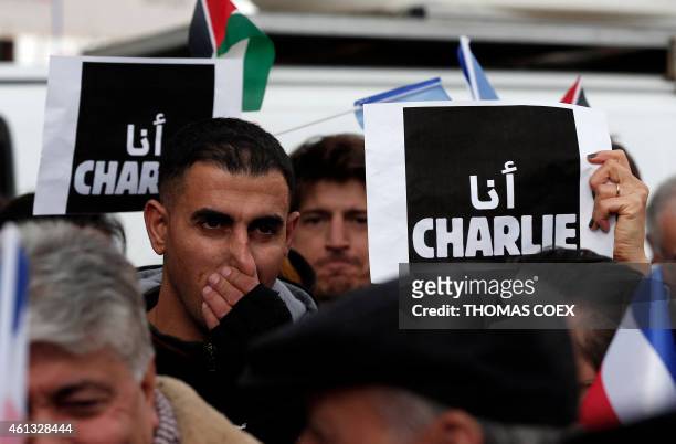 Palestinians hold placard reading in Arabic "I am Charlie" on January 11, 2015 in the center of the West Bank city of Ramallah, during a public show...