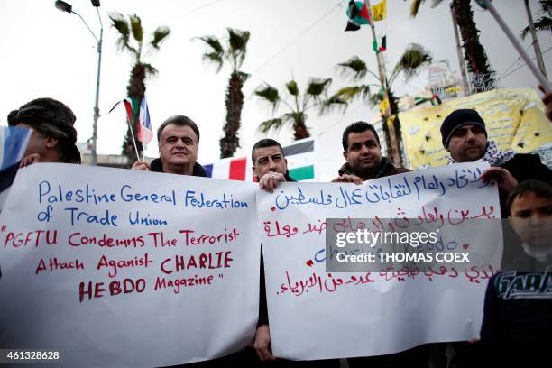 Palestinians hold placards on January 11, 2015 in the center of the West Bank city of Ramallah, during a public show of solidarity and to protest...