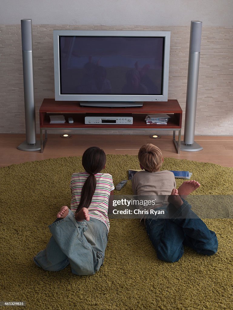 Two young kids watching the television