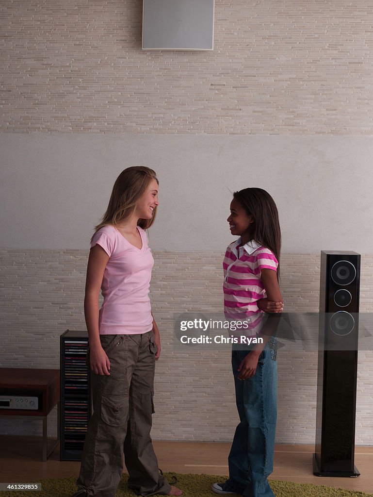 Two young girls standing in living room