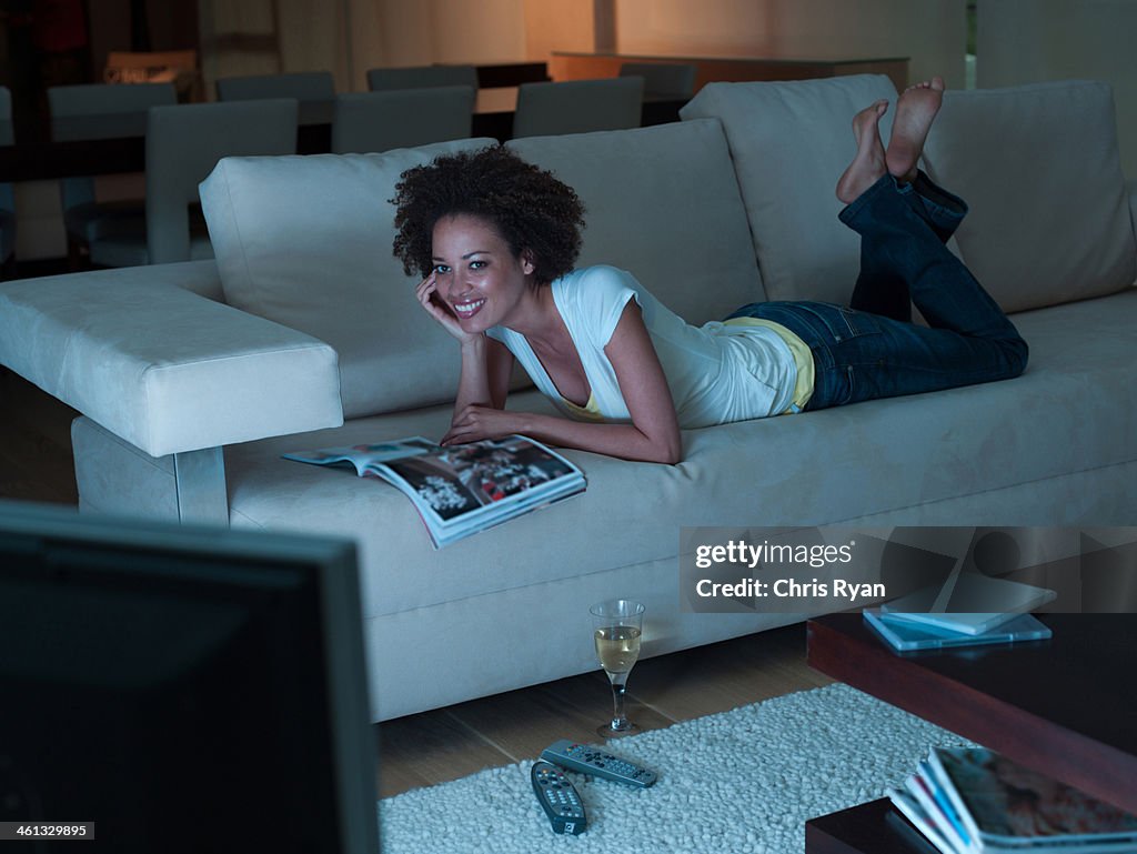 Woman watching television flipping through a magazine