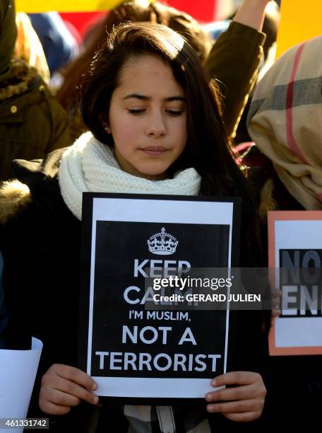 Muslim woman holds a poster in Madrid on January 11, 2015 during a show of solidarity following three days of bloodshed triggered by an attack on...