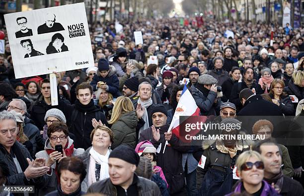 People hold a placard reading "Nous sommes Charlie" along with sketches of killed cartoonists Charb, Wolinski, Tignous and Cabu during the Unity...