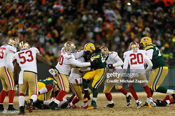 Glenn Dorsey, Eric Reid and Justin Smith of the San Francisco 49ers tackle Eddie Lacy of the Green Bay Packers during the game at Lambeau Field on...