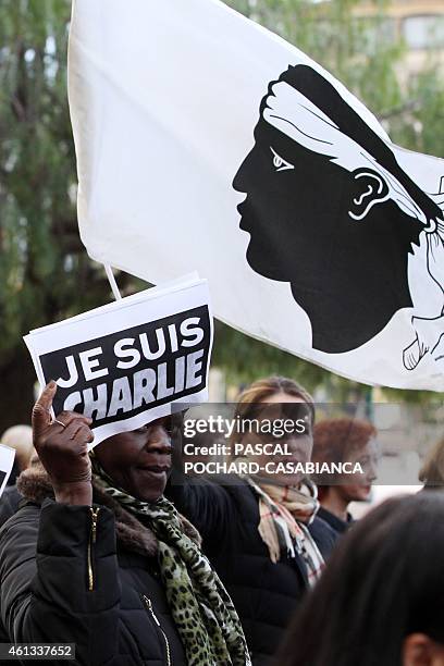 People hold a sign reading "Je suis Charlie" and the Corsican flag during the Unity rally "Marche Republicaine" that gathered 10.000 persons on...