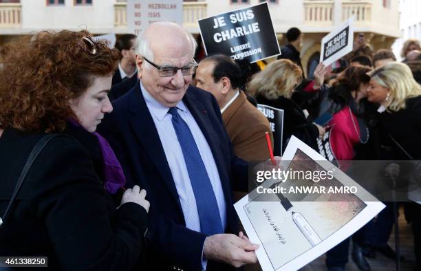 Lebanese Information Minister Ramzi Jreij holds a cartoon drawn by Lebanese cartoonist Stavro Jabra as a tribute to the slain Charlie Hebdo...