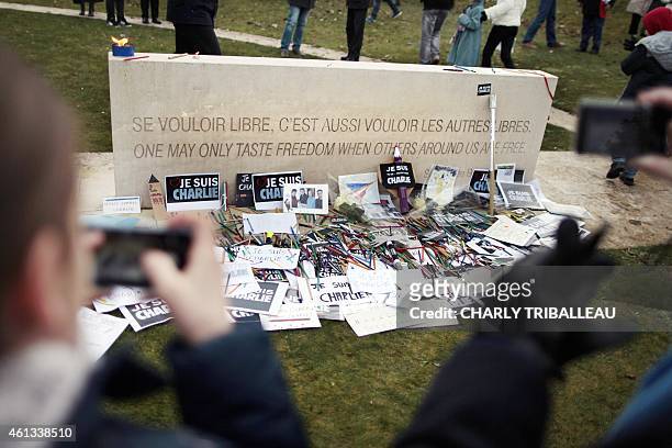 People take pictures of boards reading "I am Charlie" " put on a stele reading a quote of late French writer Simone de Beauvoir at to the war...