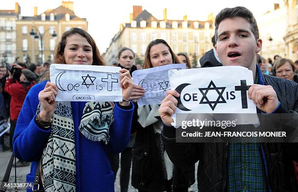 People hold signs reading "Coexist" during a unity rally on January 11, 2015 in Rennes where some 115000 people took part in tribute to the 17...