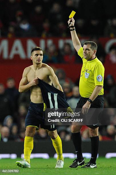 Referee Phil Dowd shows the yellow card to Southampton's Serbian midfielder Dusan Tadic for removing his shirt during his celebration after scoring...