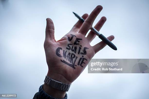 Man holds a pen aloft as people gather in Trafalgar Square to show their respect to victims of the terrorist attacks in Paris on January 11, 2015 in...
