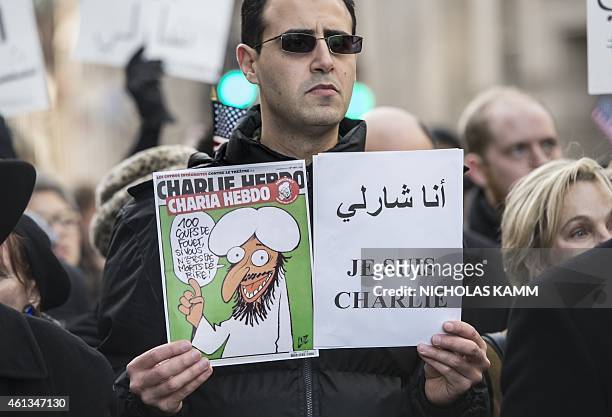 Man holds a copy of Charlie Hebdo, renamed Charia Hebdo in reference to Islamic Sharia law, as he marches in Washington on January 11, 2015 in...