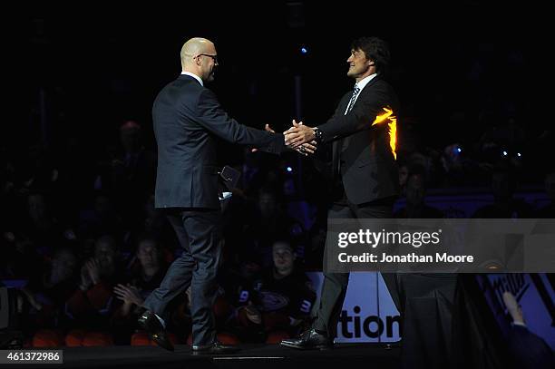 Former Anaheim Ducks player Teemu Selänne shakes hands with former NHL player Jean-Sébastien Giguère during his jersey retirement ceremony for prior...