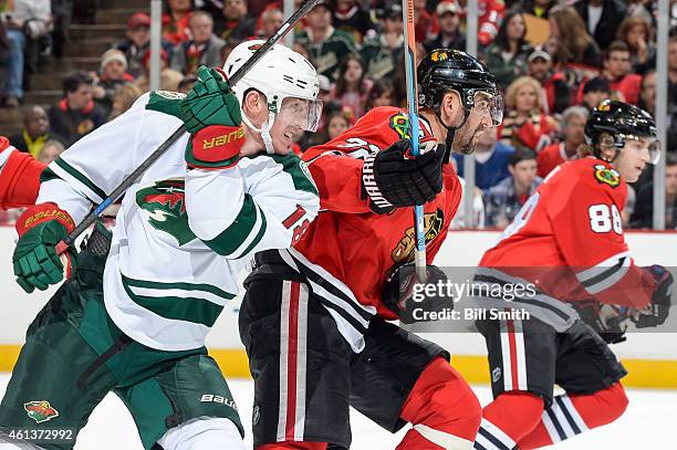 Ryan Carter of the Minnesota Wild and Michal Rozsival of the Chicago Blackhawks watch for the puck during the NHL game at the United Center on...