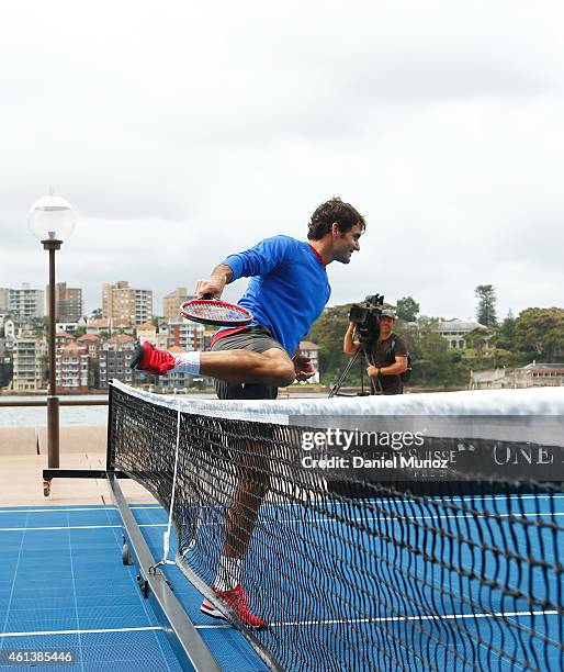 Roger Federer of Switzerland climbs the net during the launch of Fast 4 Tennis in front of the Sydney Harbour Bridge on January 12, 2015 in Sydney,...